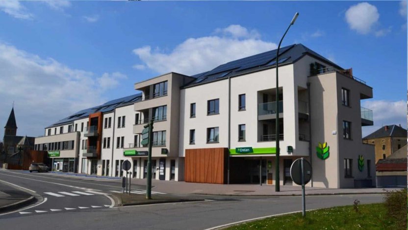 Vue d'extérieur du batiment au rond point d'Etalle qui contient une pharmacie, les bureaux de BGS et BNS. Le style est moderne et arbore des plaques en acier corten